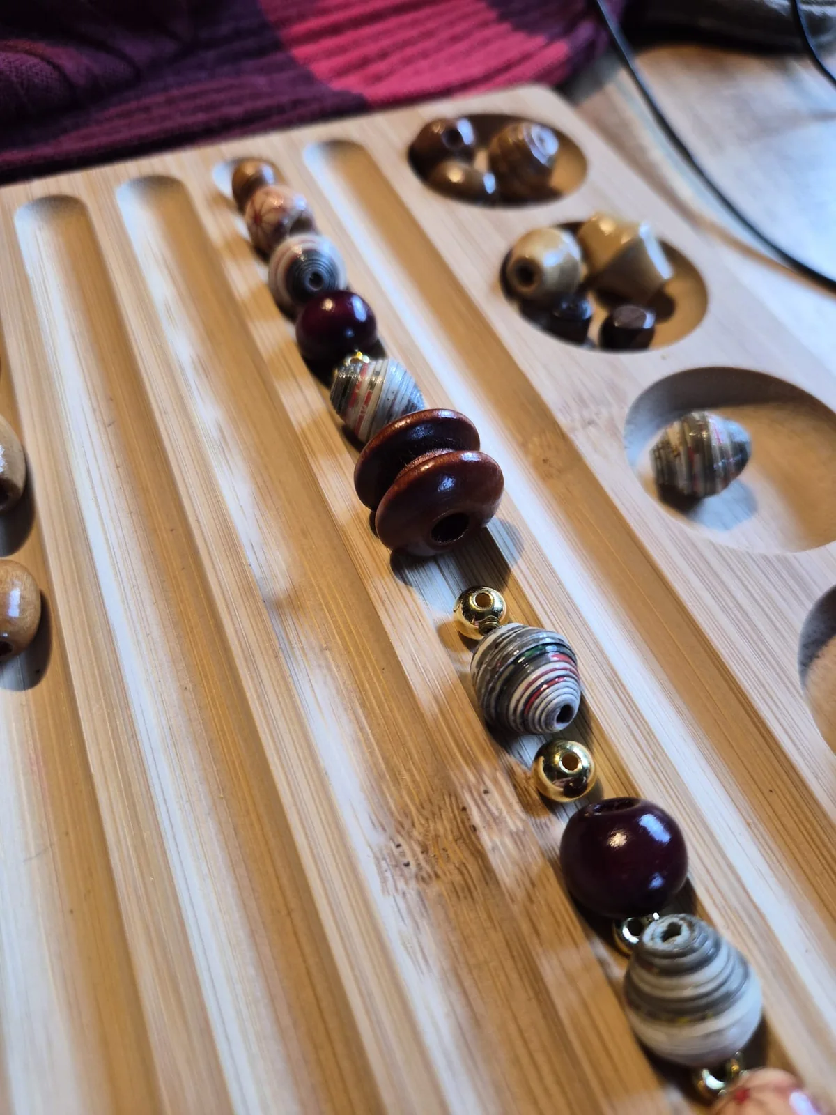 Beads being arranged on a wooden design board to interpret the outfit