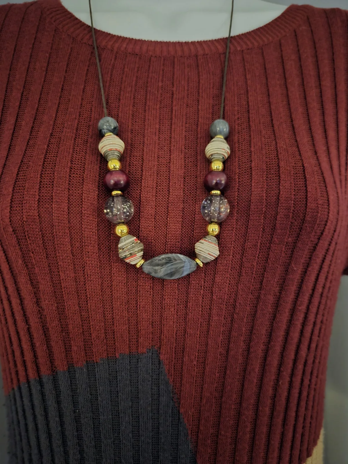 The deeper necklace interpretation worn against the wine-coloured fabric