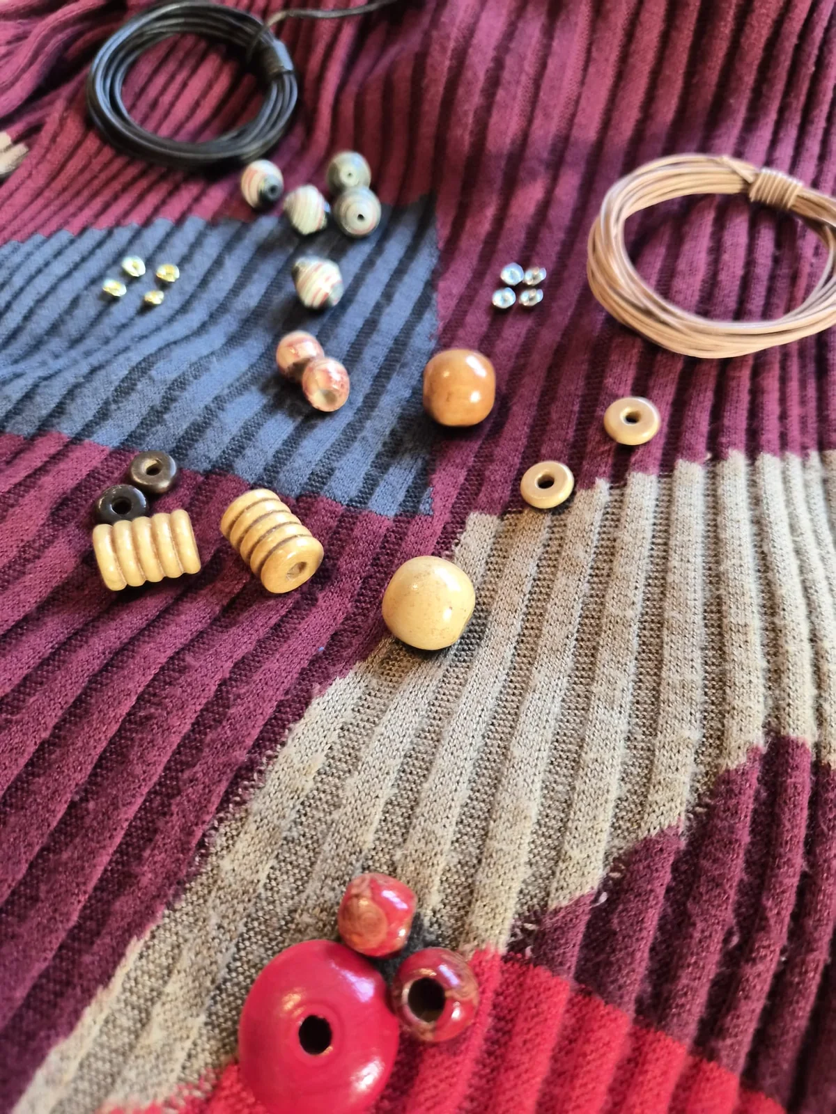 Loose necklace components arranged on a wine-coloured dress as visual inspiration